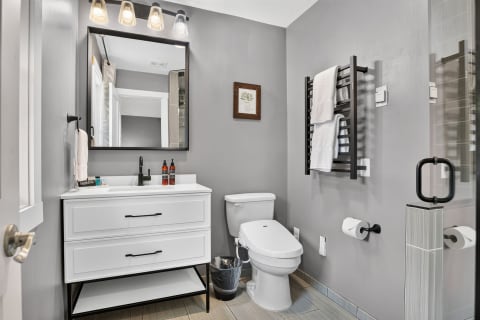 Modern bathroom featuring gray walls, white fixtures, and elegant lighting.