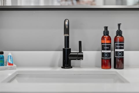 Modern sink with black faucet, lotion, hand soap, and bathroom essentials.