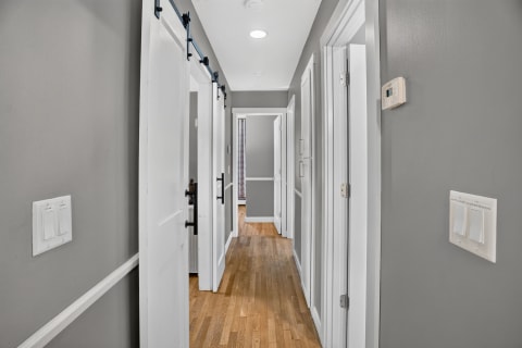 A well-designed hallway connecting rooms with hardwood floors and sleek barn-style doors.