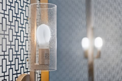 Contemporary lighting fixture with geometric wallpaper in the background.