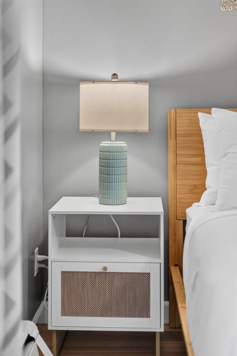 A stylish nightstand with a mint-green lamp and a wooden headboard in a tranquil bedroom.
