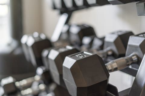 Neatly organized black hexagonal dumbbells on a rack in a modern fitness area.