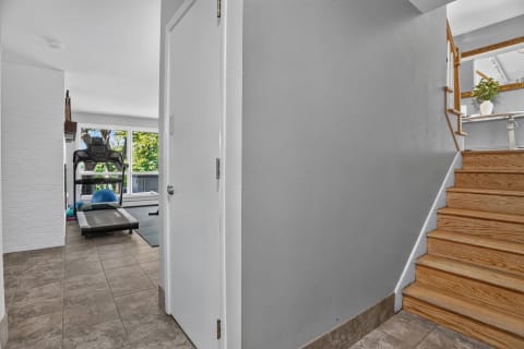 A fitness area featuring a treadmill, exercise ball, and large windows with natural light.