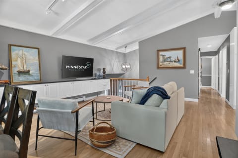 Cozy living room featuring soft seating, coastal-themed art, and a modern flat-screen TV.