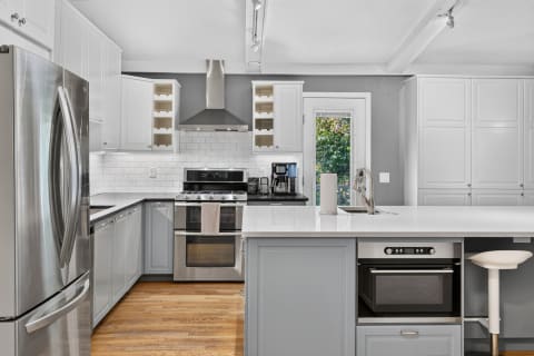Bright and modern kitchen featuring stainless steel appliances and light grey cabinetry.