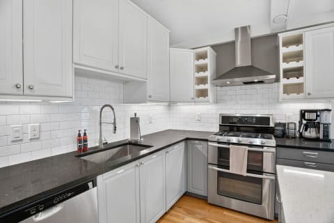 A contemporary kitchen with white cabinets, granite countertops, and stainless steel appliances.