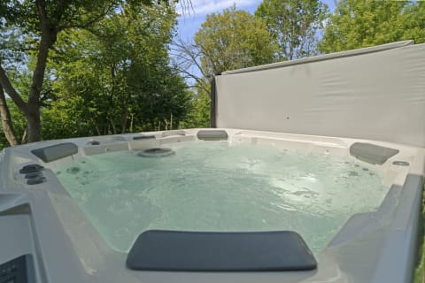A hot tub surrounded by green trees in a serene outdoor setting, inviting relaxation.