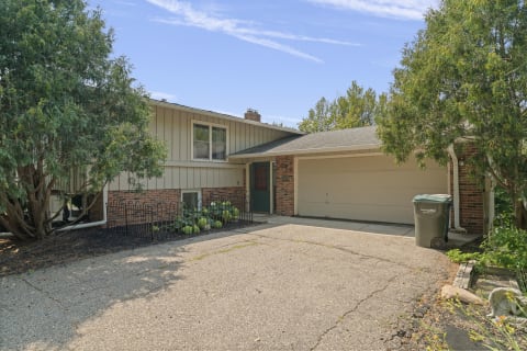 Split-level residential property with brick accents and greenery in a peaceful neighborhood.