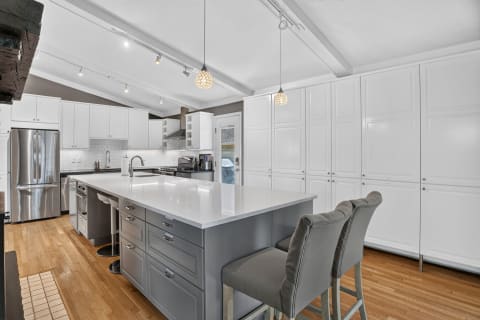 Modern kitchen with white cabinets, quartz island, and stainless steel appliances