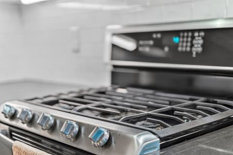 Close-up of a sleek gas range with blue-accented knobs and dark burners, showcasing a modern kitchen appliance.