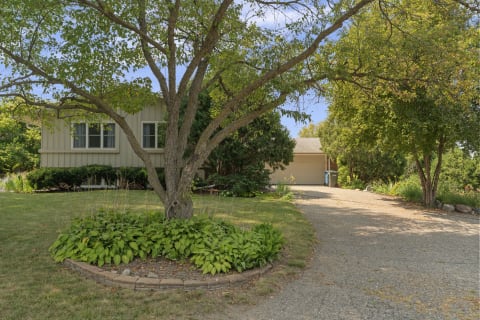Exterior view of a tranquil home framed by trees and landscaped gardens.