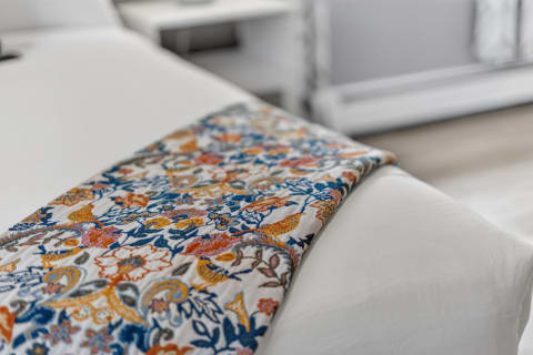 A colorful floral-patterned bed runner laid over a white bed, suggesting a cozy and inviting atmosphere.