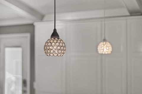 Two pendant lights with glass orbs illuminating a bright room with paneled walls.