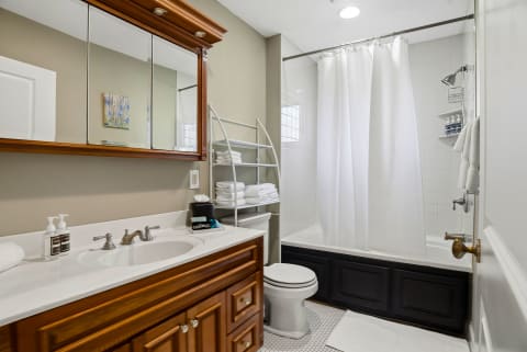 Refresh in your elegant bathroom, where crisp white tiles meet warm wood accents. Plush towels await as sunlight filters through, creating a spa-like sanctuary for your stay.