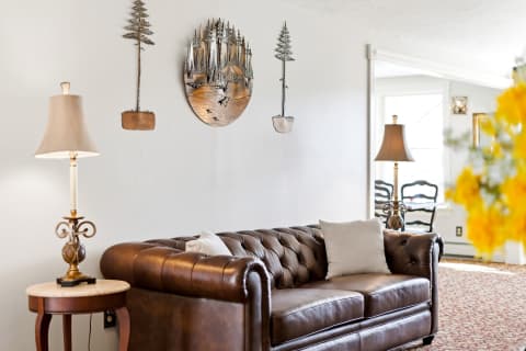 Sink into this rich brown leather sofa and unwind in your elegantly decorated living space, where mountain-inspired art and warm lighting create a cozy retreat for relaxation.