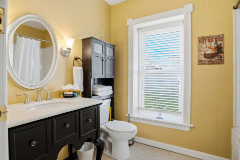 A stylish bathroom featuring a black vanity, elegant mirror, and sunny yellow walls.