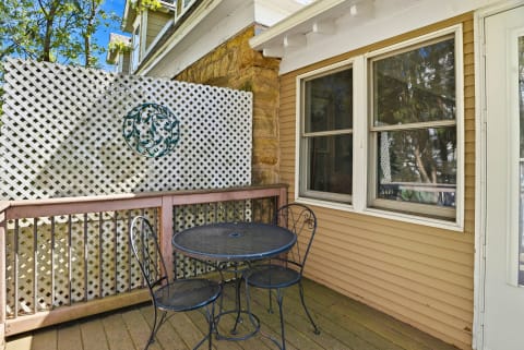 A private deck with a bistro table and chairs, featuring a lattice wall and decorative metal art.