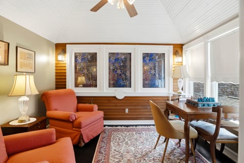 Warm reading nook with coral armchairs, stained glass windows, and a wooden desk.