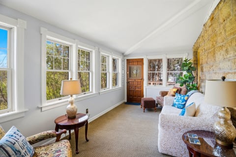 A sunroom featuring large windows, cozy seating, and a welcoming entryway.