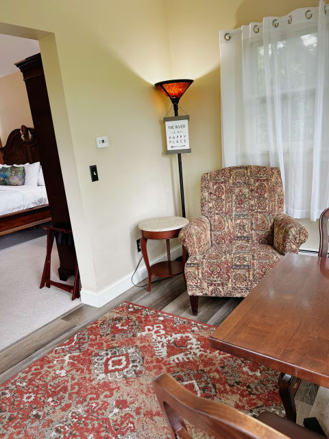A cozy corner featuring a patterned armchair, a floor lamp, and a round side table, set in a comfortable living space.
