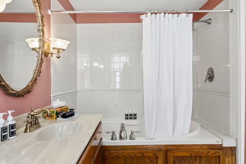 A beautifully designed bathroom with a deep soaking tub, shower, and elegant vintage-style lighting.