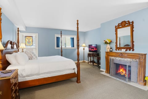 A serene bedroom with blue walls, a four-poster bed, and a fireplace.