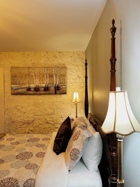 Elegant bedroom featuring a four-poster bed with plush pillows and ambient lighting.
