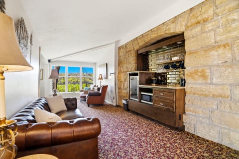 Cozy living room featuring a leather sofa, stone archway, and large windows with a view.