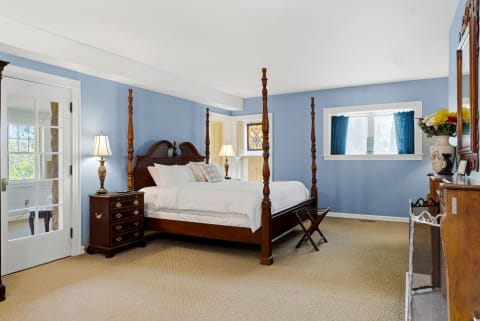 Spacious bedroom with blue walls, a four-poster bed, and a vintage dresser.