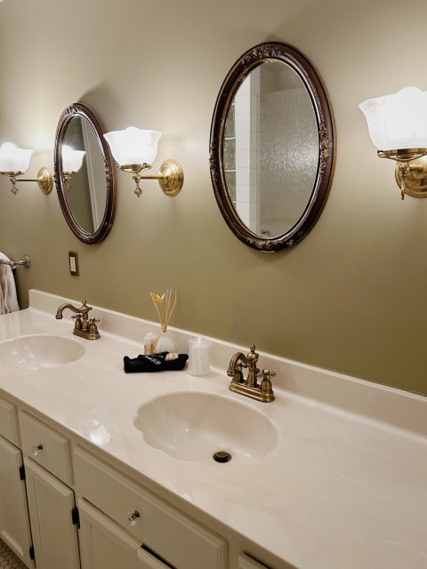 A luxurious dual-sink vanity with brass fixtures and decorative mirrors in a bathroom setting.