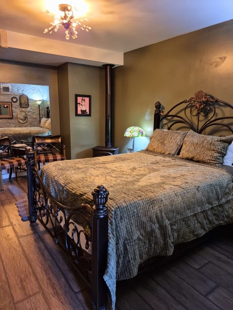 A cozy bedroom featuring a wrought-iron bed with quilted bedding, olive green walls, and decorative accents.