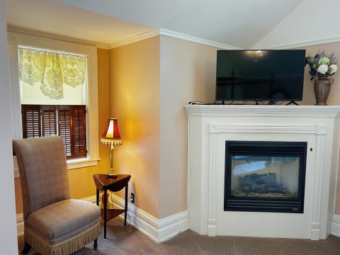 Cozy room corner with an armchair, fireplace, and decorative lamp.