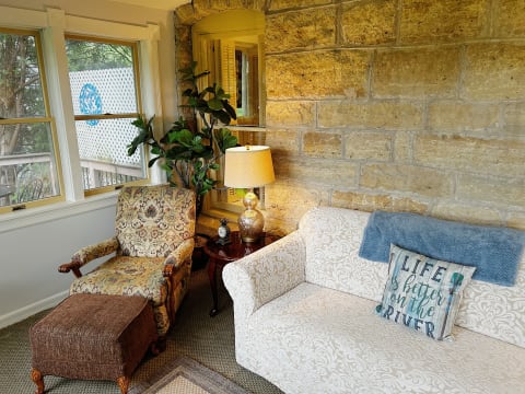 Cozy living room featuring stone walls, elegant seating, and natural light.
