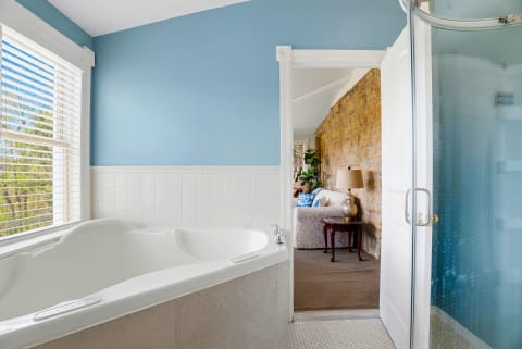 Interior view of a bathroom featuring a deep soaking tub and coastal blue walls with a glimpse into a cozy living area.