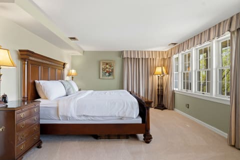 A serene bedroom featuring a wooden bed, soft linens, natural light, and elegant décor.