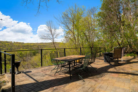 Spacious terrace overlooking green hills with outdoor dining and seating areas.
