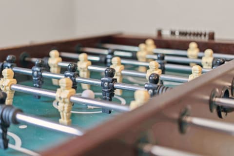 Close-up of a foosball table featuring black and beige players and a ball.
