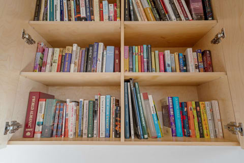 A wooden bookshelf filled with a variety of books across several shelves.