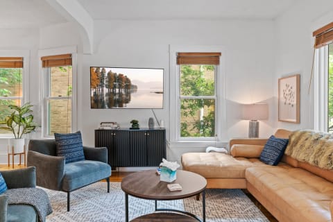 Cozy living room featuring leather furniture, a flat-screen TV, and natural light.