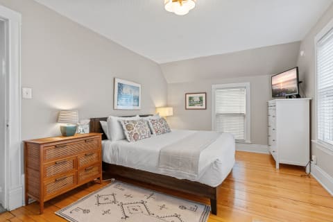 Cozy bedroom with king-sized bed, wooden dresser, and natural light.
