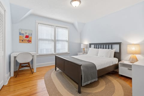 Cozy bedroom with blue walls, gray bed, desk, and beach-themed artwork.
