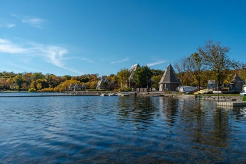 A tranquil lakeside scene with autumn trees and unique buildings.