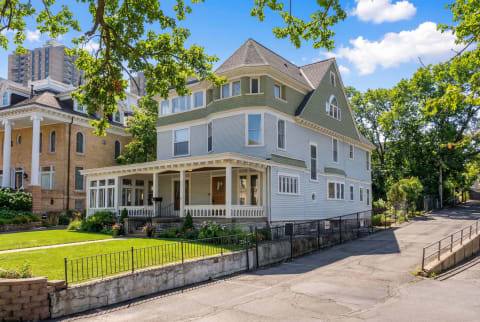 Victorian property with wraparound porch in a residential area, showcasing a blend of old and new architecture.