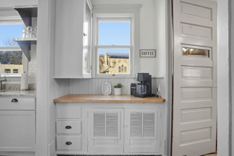 Bright kitchen corner with a coffee maker and a view of historic buildings outside.