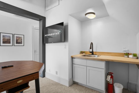 A cozy third-floor game room featuring a kitchenette, a wooden table, and modern decor.