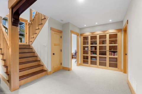 Interior view of a modern foyer with staircase and wooden bookshelf.