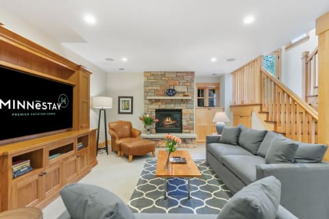 Cozy living room featuring a stone fireplace, gray couch, and wooden accents.