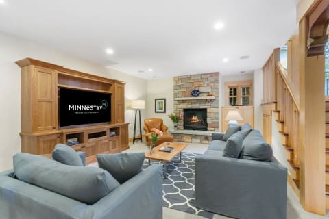 Cozy living room with stone fireplace, modern television, and gray couches.