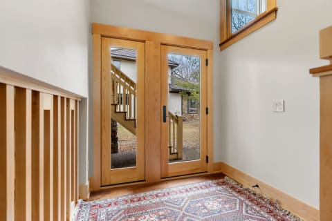 Entrance hallway featuring double wooden doors and a patterned rug.