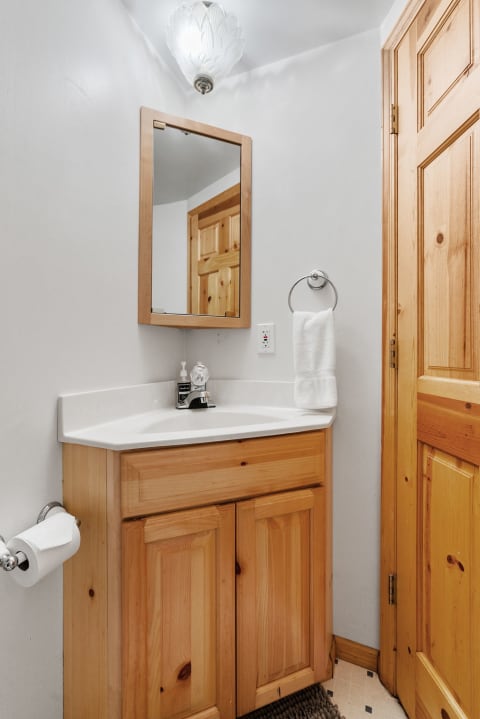 Modern small bathroom with wooden vanity and mirror.